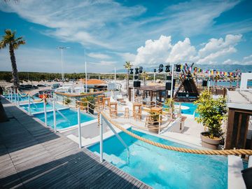 Pool terrace with palm trees and white cabanas – Nomad Beach Club, Zrce Beach