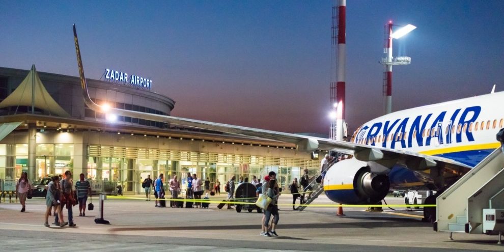 Zadar Airport terminal at dusk, passengers boarding a plane